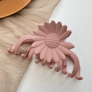 Detailed close-up of a dusty pink matte sunflower hair claw clip on a soft textured surface
