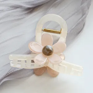 Detalle de pinza para pelo de acetato con flor rosa y resorte metálico dorado