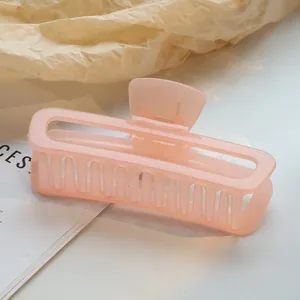 Detailopname van een semi-transparante perzikroze rechthoekige holle haarklem