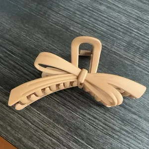 Makro-Detail der großen mattbeigen Haarklammer mit Schleife und Metallfeder