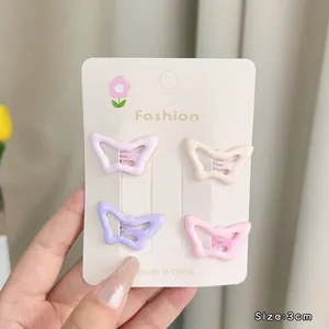 Close-up of four colorful 3cm hollow butterfly hair clips held in hand for size detail