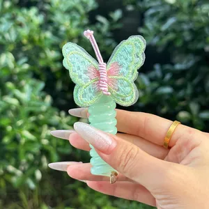 Détail d'un élastique à cheveux papillon brodé vert menthe avec bande spirale en main