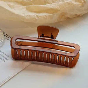 Detail van een grote amberbruine vierkante haarklem met een hol transparant design