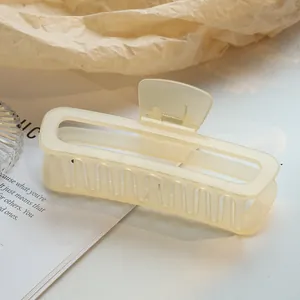 Close-up van een grote crèmekleurige holle rechthoekige haarklem op een tijdschrift