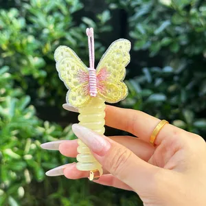 Détail d'un accessoire à cheveux papillon brodé jaune avec fil spirale de téléphone