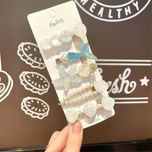 Macro shot of 5-piece sea-themed hair clips with shells, pearls and mermaid tails
