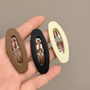 Nahaufnahme von drei matten ovalen BB-Haarclips in Braun, Schwarz und Beige