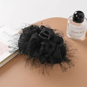 Dettaglio di un elegante fermaglio per capelli in piume di struzzo nere con glitter argento