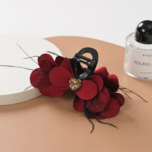 Dettaglio della molletta per capelli con petali rossi, piume nere e cristallo a cuore