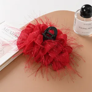 Dettaglio molletta per capelli rossa con piume di struzzo accanto a un profumo di lusso