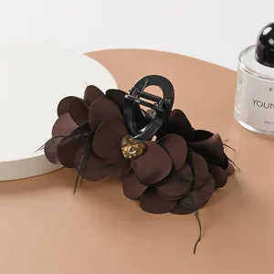 Dettaglio del fermaglio per capelli a fiore marrone con gemma a cuore e piume nere