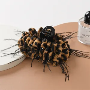 Detail of leopard print hair claw clip featuring black feathers and sparkling rhinestones