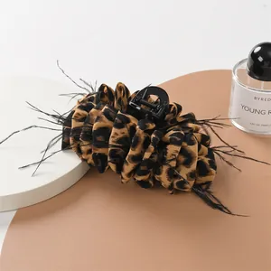 Leopard print hair claw clip with black feathers on a stylish display surface