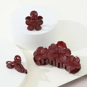 Détails de trois pinces à cheveux rouge foncé à fleurs et nœud sur socle blanc