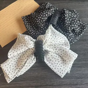 Detailed view of two vintage polka dot bow hair clips in black and white chiffon fabric