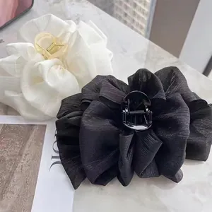 Oversized ruffled seersucker lace claw clips in cream and black on marble surface