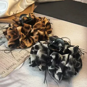 Large leopard print hair claw clip with black feather trim and silk fabric finish