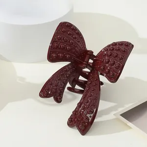 Dettaglio molletta per capelli a fiocco bordeaux con elegante trama a rilievo