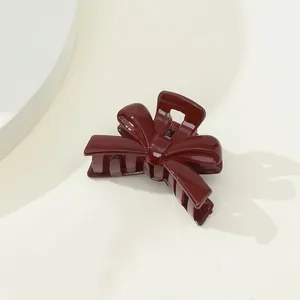 Detail of burgundy glossy bow-shaped hair claw clip with a ceramic-like polished finish