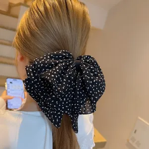 Vintage black polka dot bow hair clip for women styled on a half-up ponytail
