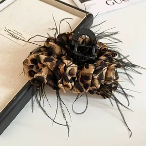 Detailed view of large leopard print hair claw clip featuring black feather trim details