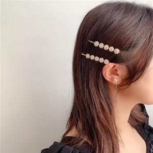 Detailansicht der goldenen Blumen-Haarspangen und Herz-Quastenohrring an einem Model
