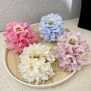 Set of four floral hair claws in pastel chiffon colors on a round wooden tray