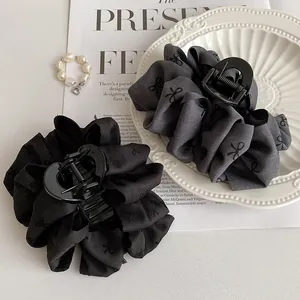 Detail of large black fabric hair claws with bow texture on vintage magazine background
