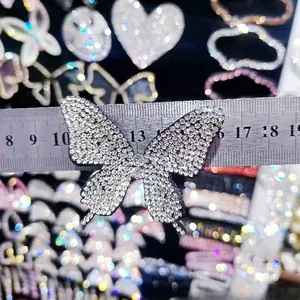 Dettaglio del fermaglio a farfalla con strass che mostra la larghezza di 6cm su un righello