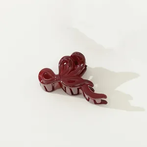 Vue détaillée de la pince à cheveux rouge foncé brillant avec un design de ruban élégant