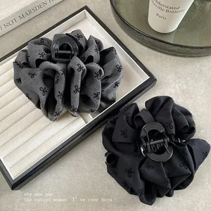 Close-up of large floral fabric hair claw clips with bow patterns in grey and black colors