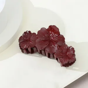 Gros plan sur une pince à cheveux rouge foncé avec design floral triple élégant