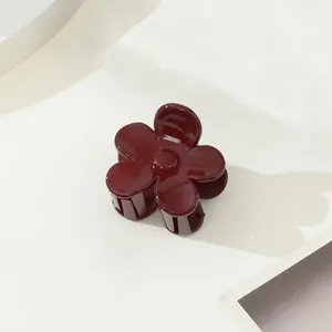 Détail d'une pince à cheveux fleur bordeaux brillant sur un support géométrique