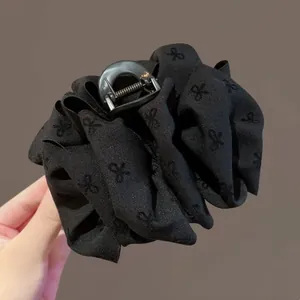 Detail of black satin hair claw clip with embroidered butterfly bows and sturdy metal spring