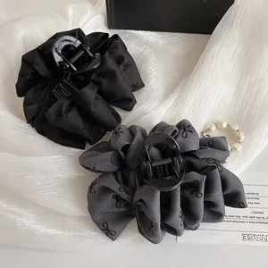 Elegant large black bubble bow hair claw clip with vintage pattern on silk background