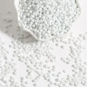 Perles de rocaille blanches polies pour bijoux DIY dans un bol en porcelaine blanc