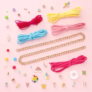 DIY-Schmuckset mit bunten CCB-Perlen, Anhängern und Wildlederband auf rosa Hintergrund