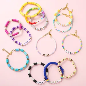 Detailopname van kleurrijke DIY kralenarmbanden met letterbedels op een roze achtergrond