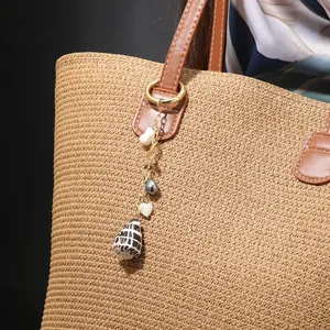 Detail of seashell and pearl pendant charm hanging on a straw tote bag handle