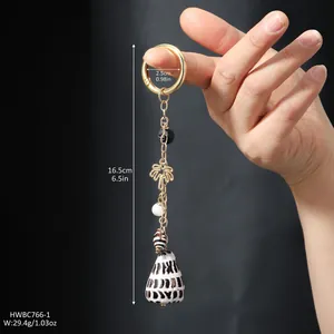 Detail shot of ocean shell keychain with gold chain, black beads and coconut tree charm