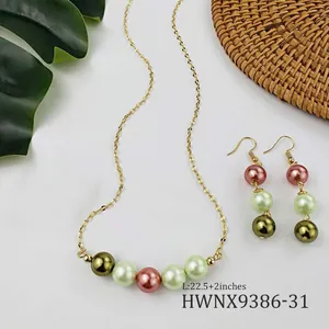 Dettaglio set orecchini e collana con perle di conchiglia multicolore e foglie decorative