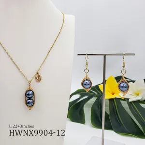 Détail d'une parure de bijoux en perles avec fil doré et breloque feuille tropicale