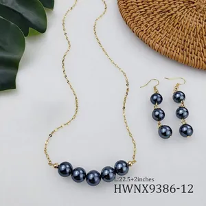 Dettaglio della collana dorata con cinque perle scure e orecchini a tre perle coordinati