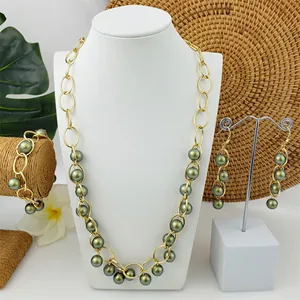 Driedelige sieradenset met gouden ringen en pauwgroene parels gepresenteerd op stands