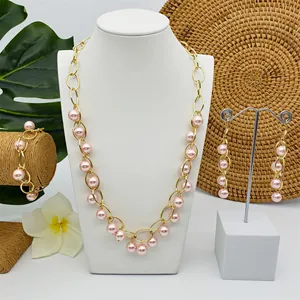 Detail van de roze parel sieradenset met gouden schakelketting en oorbellen
