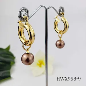 Detailed view of vintage gold hoop earrings with shell pearl charms on T-shaped stand