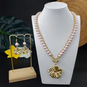 Detailansicht von goldenem Hibiskus-Schmuckset mit Halskette und rosa Perlen