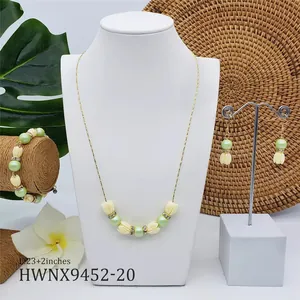 Détail de la parure de bijoux avec perles de jasmin blanc et perles vertes sur présentoir