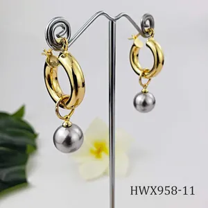 Detail of 18K gold hoop earrings with silver-grey shell pearls on a metal stand