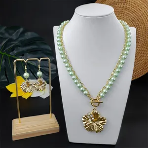 Detail eines goldenen Hibiskus-Schmucksets mit grünen Perlen auf einer Büste